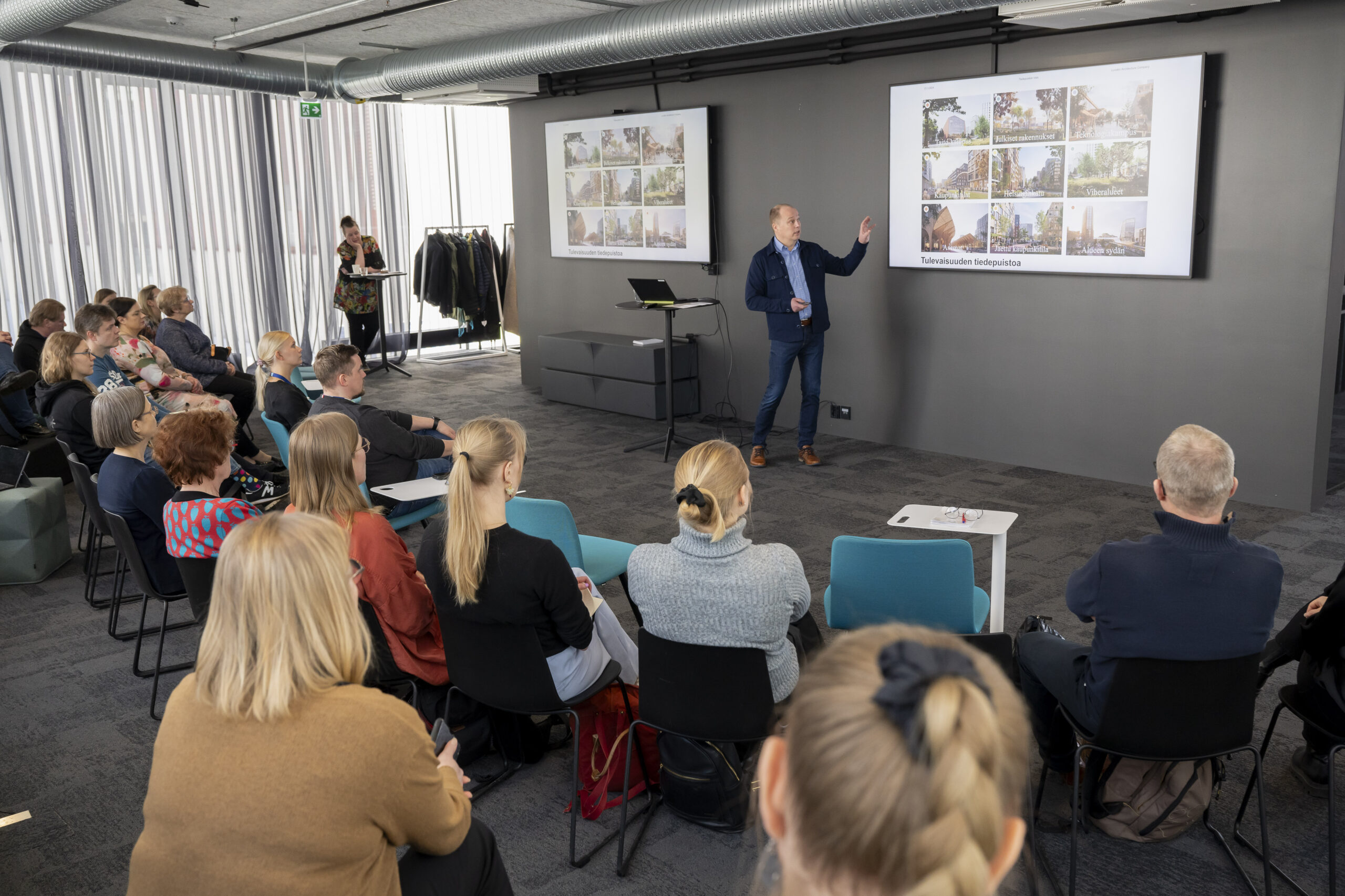 Yleisöä seuraamassa esiintyjän PowerPoint-esitystä.